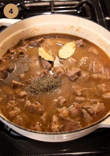 adding stock, bay leaves and tyhme to lamb pieces to make stew.