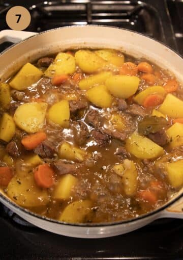 adding potatoes and broth to lamb stew in a large pot.