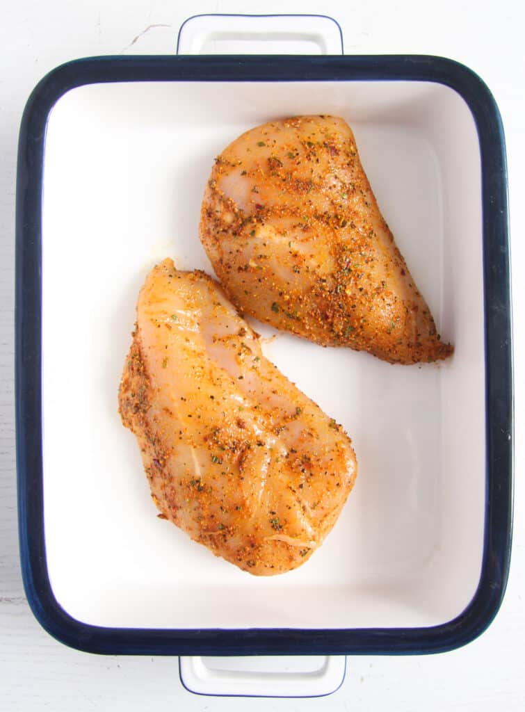 chicken marinating in a white tin.