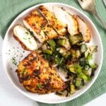 chicken with paprika marinade, one sliced on a plate with leeks.