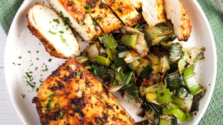 chicken with paprika marinade, one sliced on a plate with leeks.