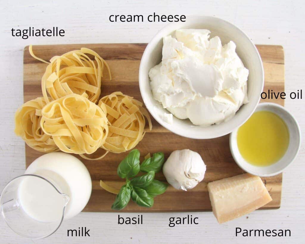 tagliatelle, cream cheese, oil, basil, garlic, milk, parmesan on a wooden board.