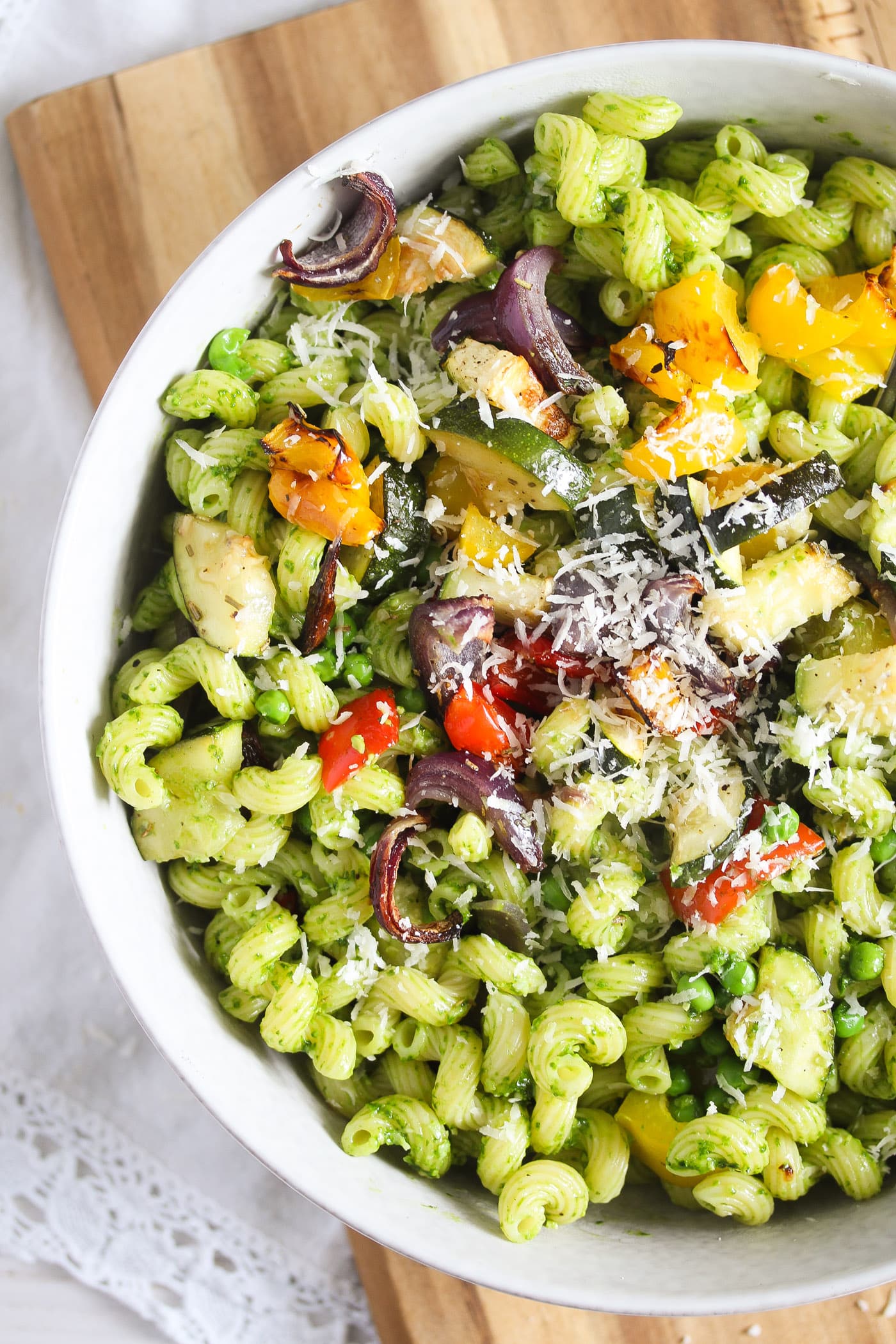 veggie pasta with pesto and parmesan in a white bowl