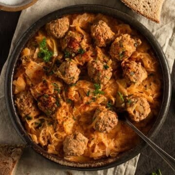 german meatballs with sauerkraut in a large bowl with a spoon in it.