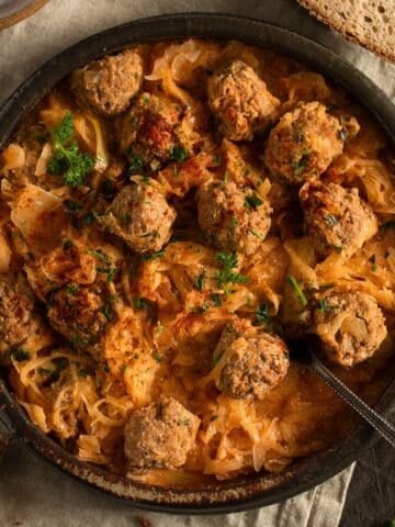 german meatballs with sauerkraut in a large bowl with a spoon in it.