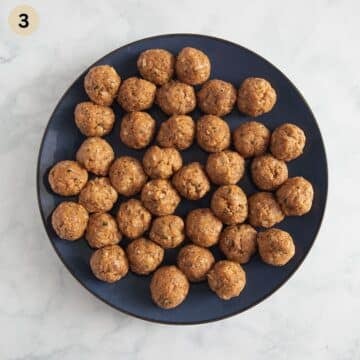 many small german meatballs before cooking on a large plate.