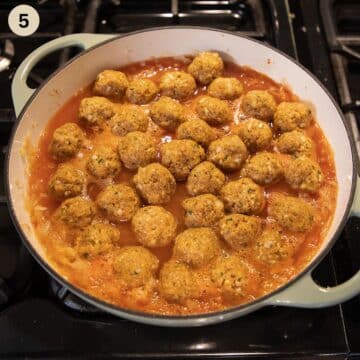 adding many small meatballs to a pot full of sauerkraut.