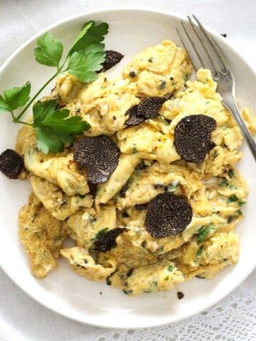 truffle eggs on a small white plate with fork and parsley.