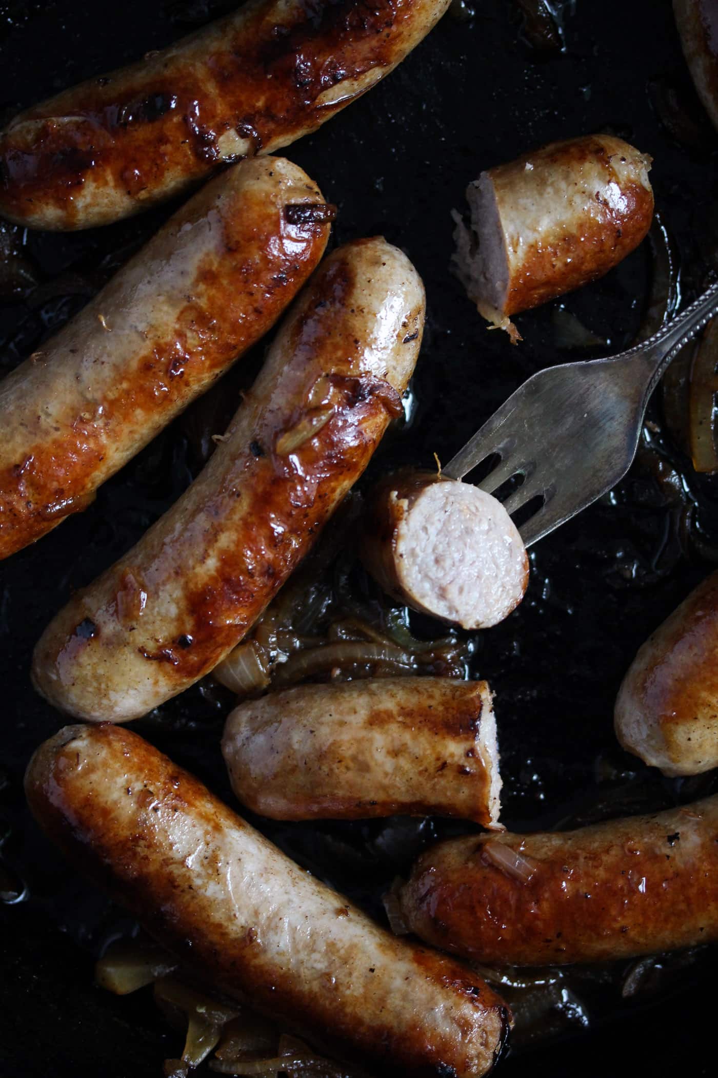bratwurst cooked on the stove top in a pan.