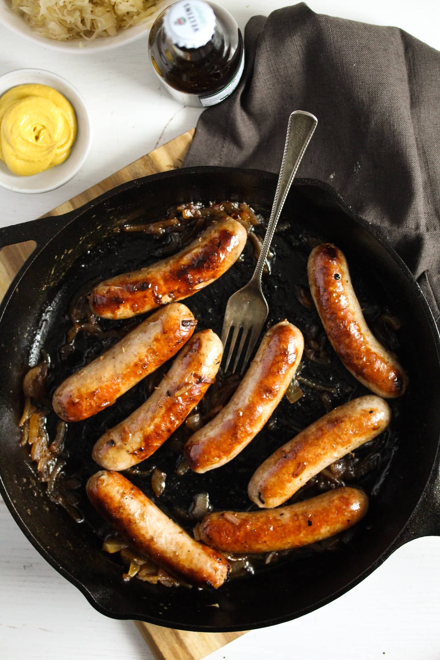 brats in a pan served with a bowl of mustard.