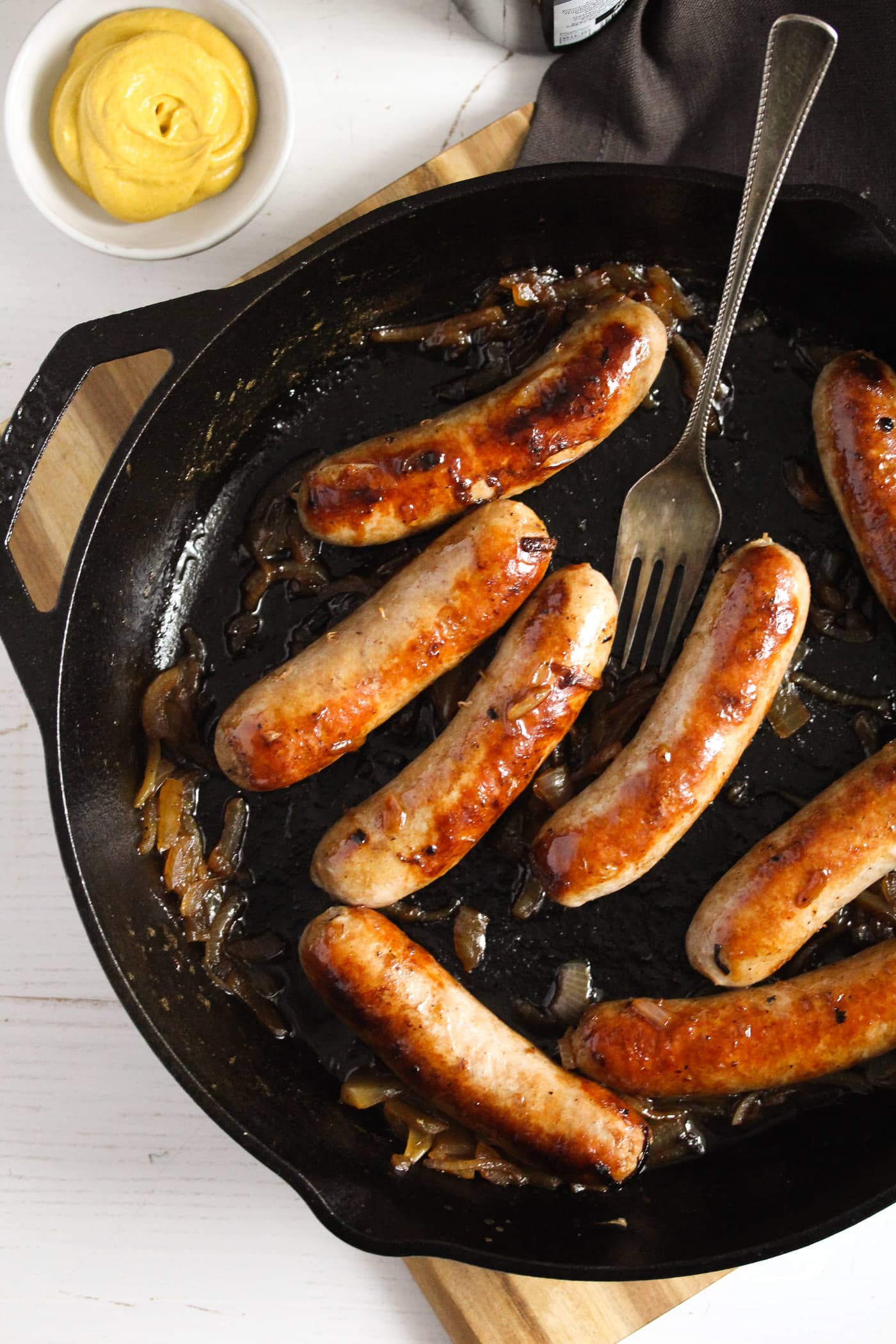 overhead shot of a black pan with bratwurst in it.