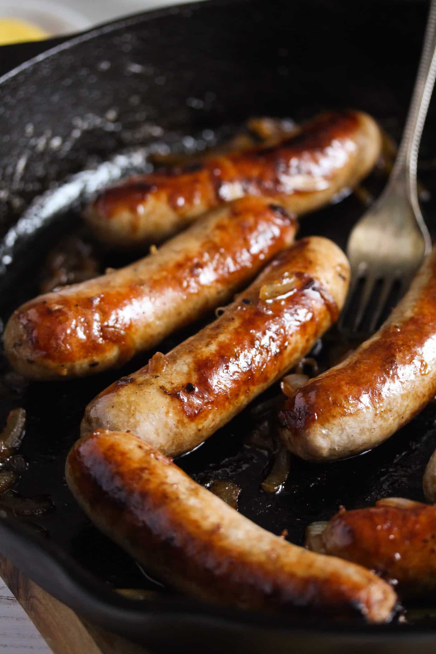 brown sausages in a cast iron pan.