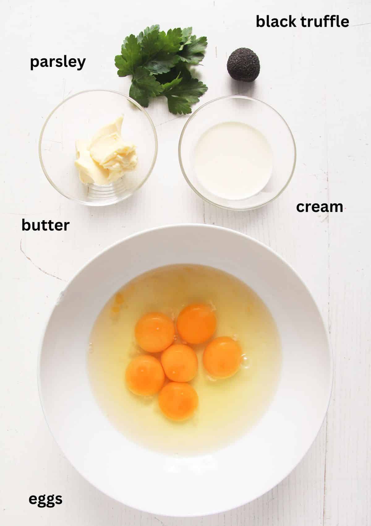labeled ingredients for making scrambled eggs with black truffle, butter, cream and parsley.