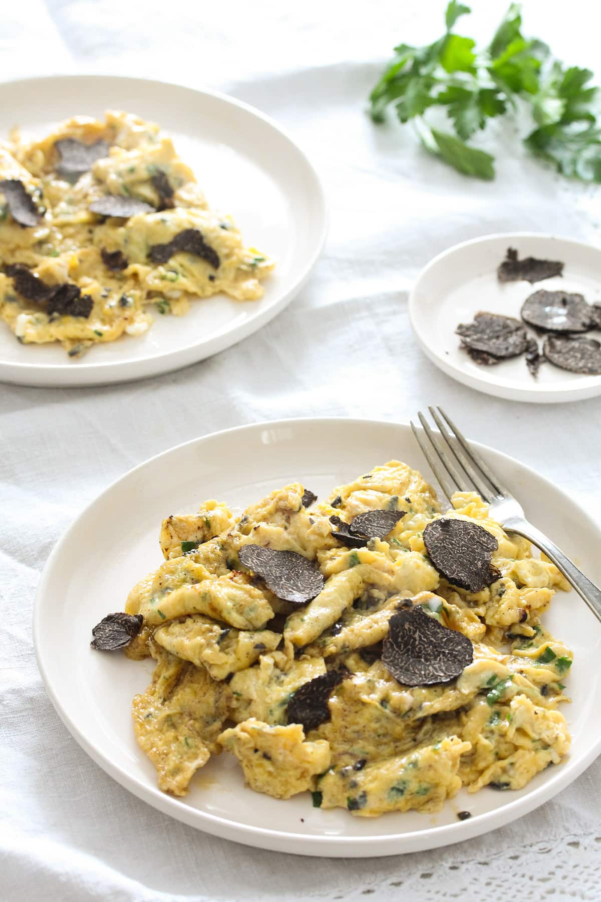 two plates for truffled eggs with black truffle slices on top.