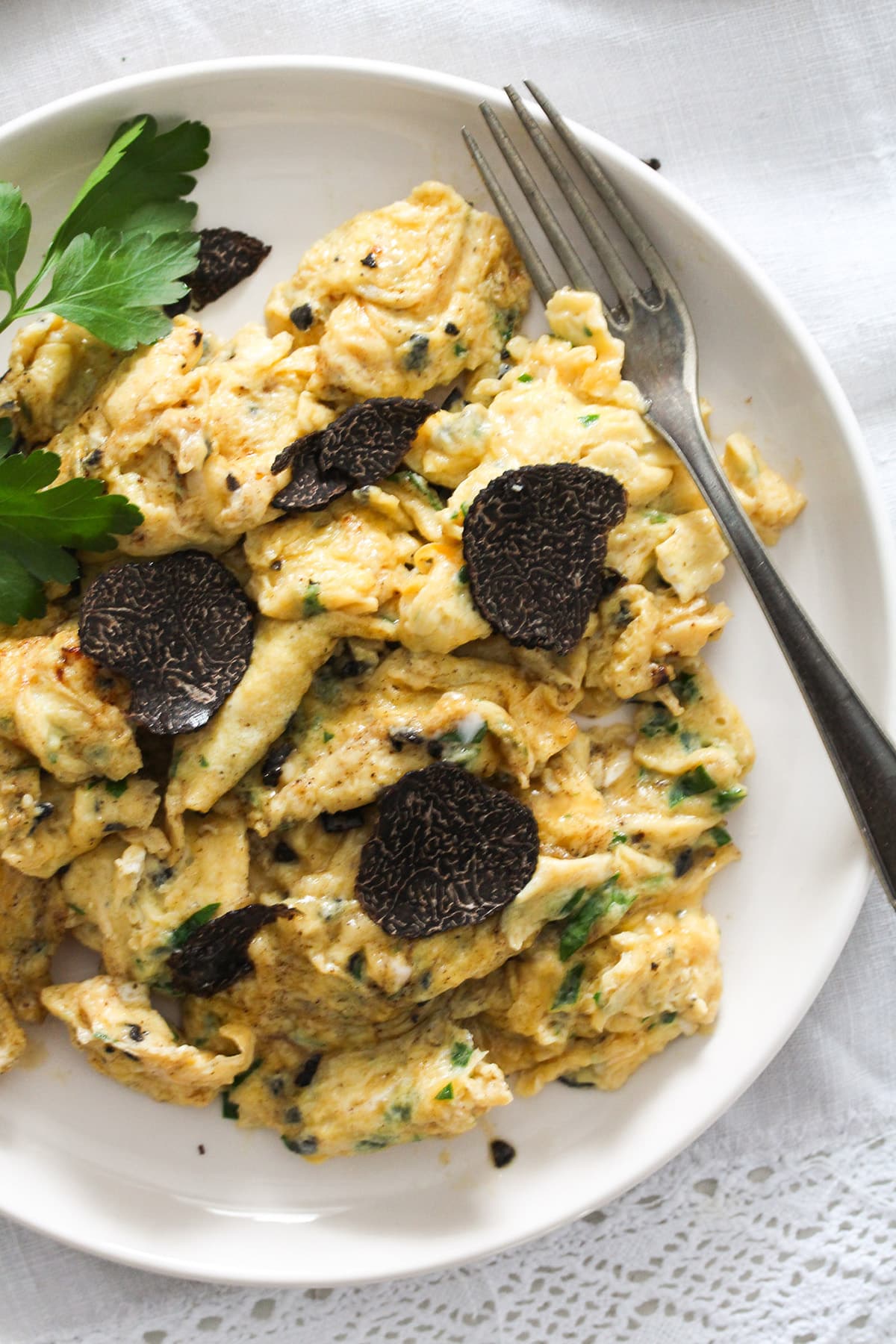 truffled scrambled eggs with truffle slices on top and a fork.