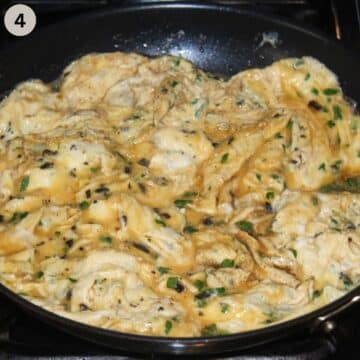 scrambled eggs with parsley in a pan.