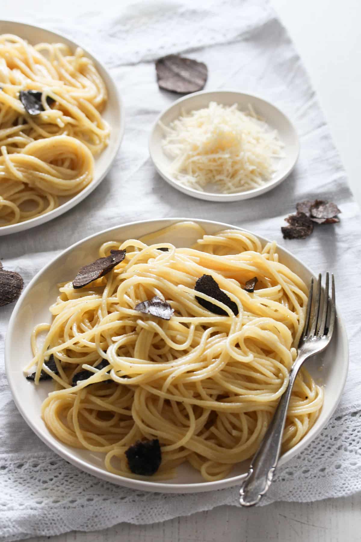 plates with truffle pasta and a small plate with parmesan.