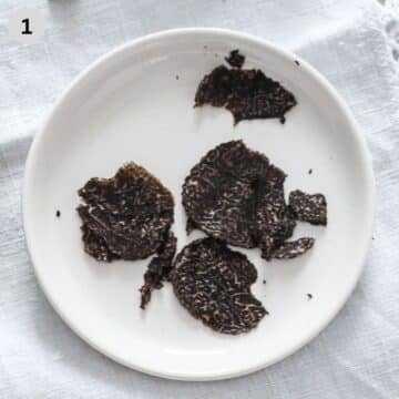 shaved black truffles on a small white plate.