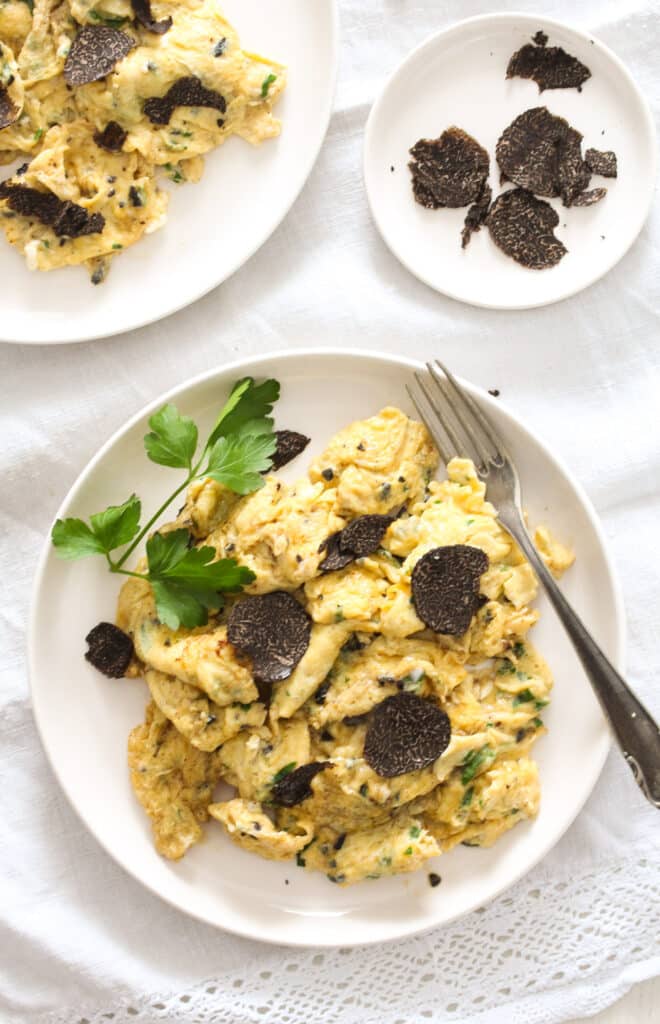 overhead shot of a plate with scrambled eggs and one with shaved truffles.