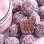 many chocolate champagne truffles coated with pink colored sugar.