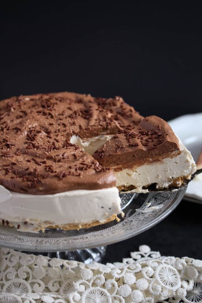 slicing a cheesecake topped with chocolate cream.