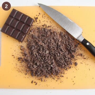 chopping chocolate with chef's knife on a cutting board.