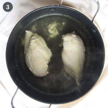 two pieces of boiled chicken breast in a pot.