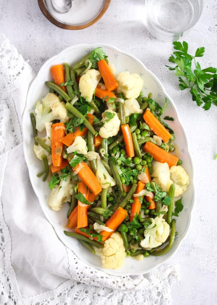 carrots, cauliflower, peas, green beans cooked in butter on a large platter.