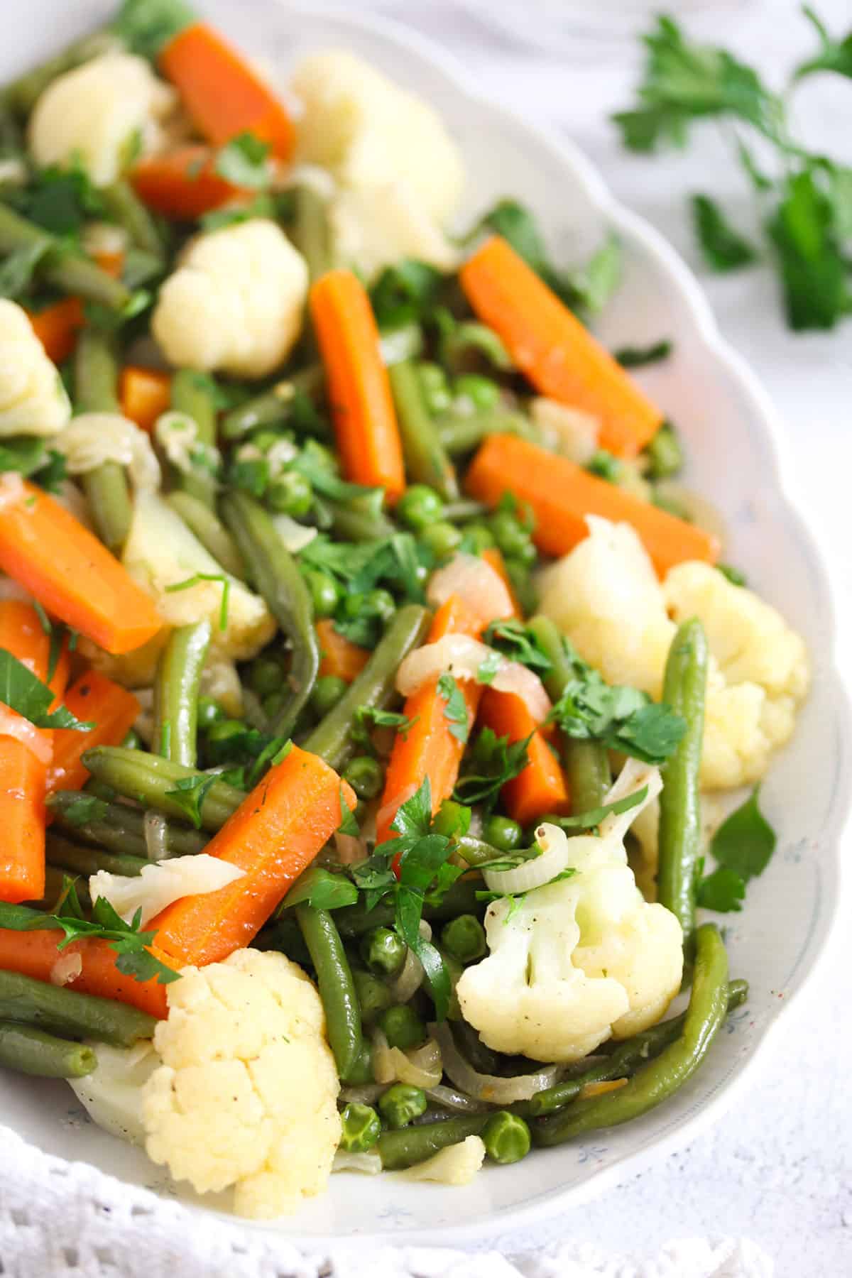 platter full of veggies cooked in butter and served as a side dish.