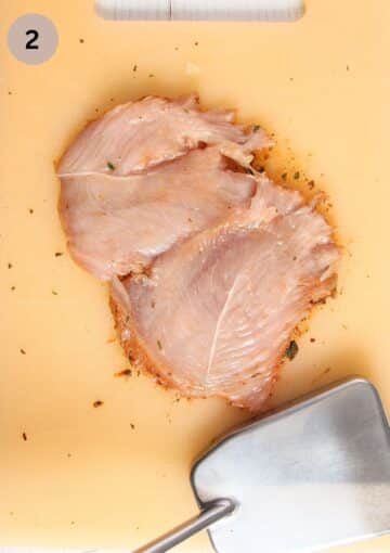 butterflied and pounded chicken breast pieces and a meat mallet.