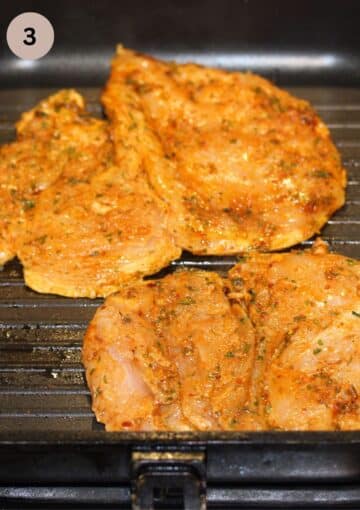 two pieces of uncooked, marinated chicken breast in a grill pan.