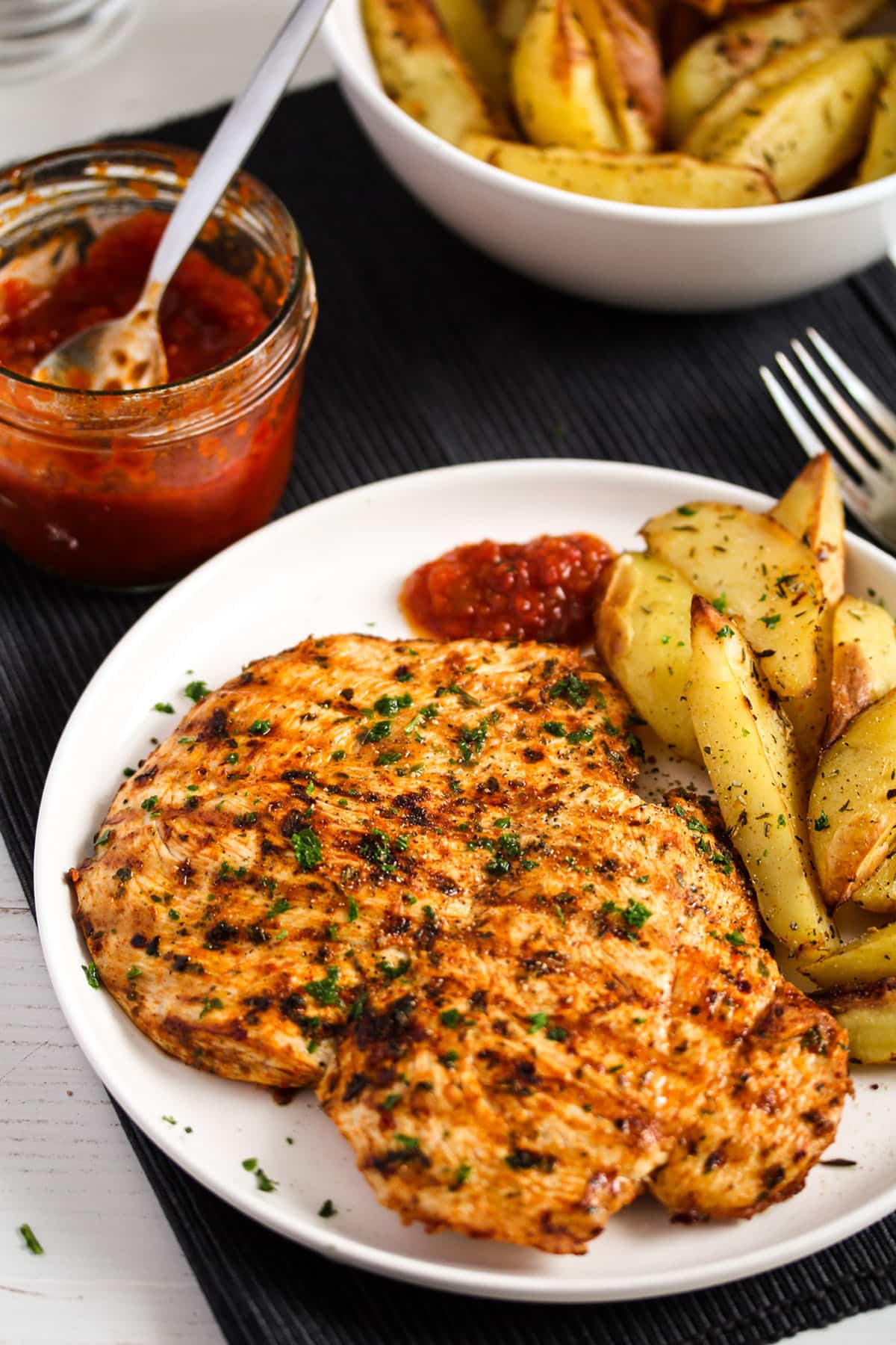 plate with grilled chicken breast, potatoes and dip.