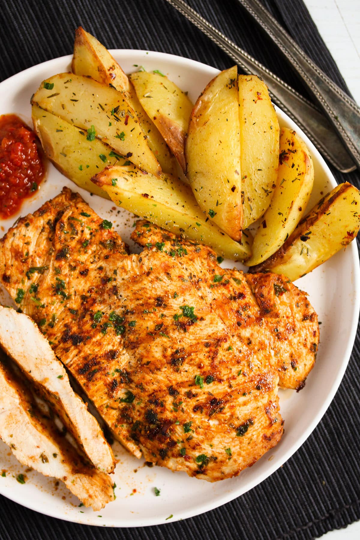 plate with nando butterfly chicken breast served with potatoes and dip.