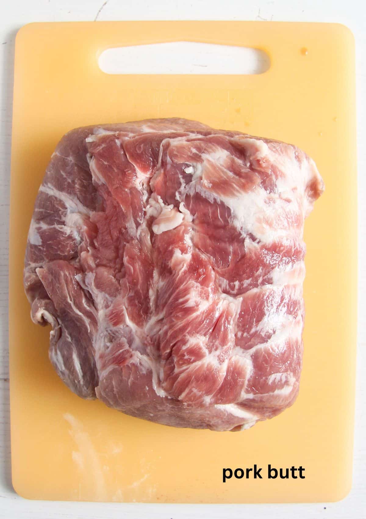 a large piece of marbled pork butt on a cutting board.