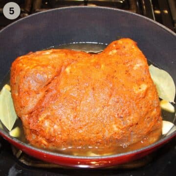 one seasoned, raw pork butt in a dutch oven.