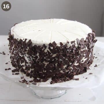 covering the sides of a black forest cake with chocolate shavings.