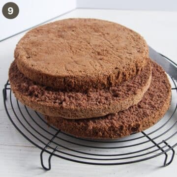 three freshly cut layers of chocolate sponge on a wire rack.