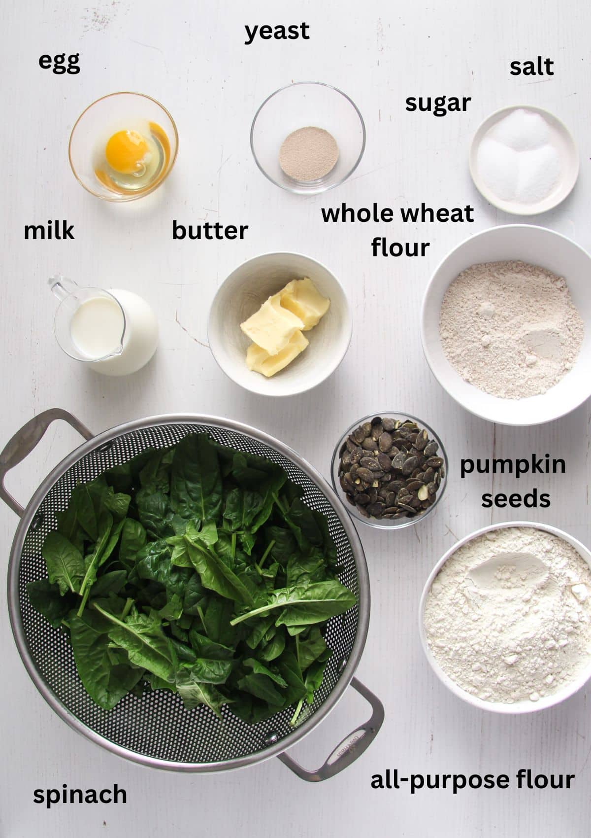 labeled ingredients for making bread with fresh spinach, flour, butter, pumpkin seeds, and yeast.