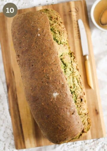 a loaf of baked bread on a wooden cutting board.