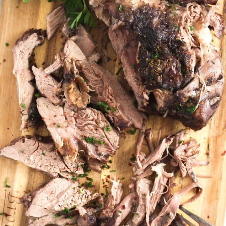 lamb shoulder in the slow cooker shredded on a wooden board.