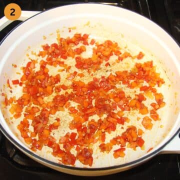 diced carrots and onions stirred with tomato paste in a pot.