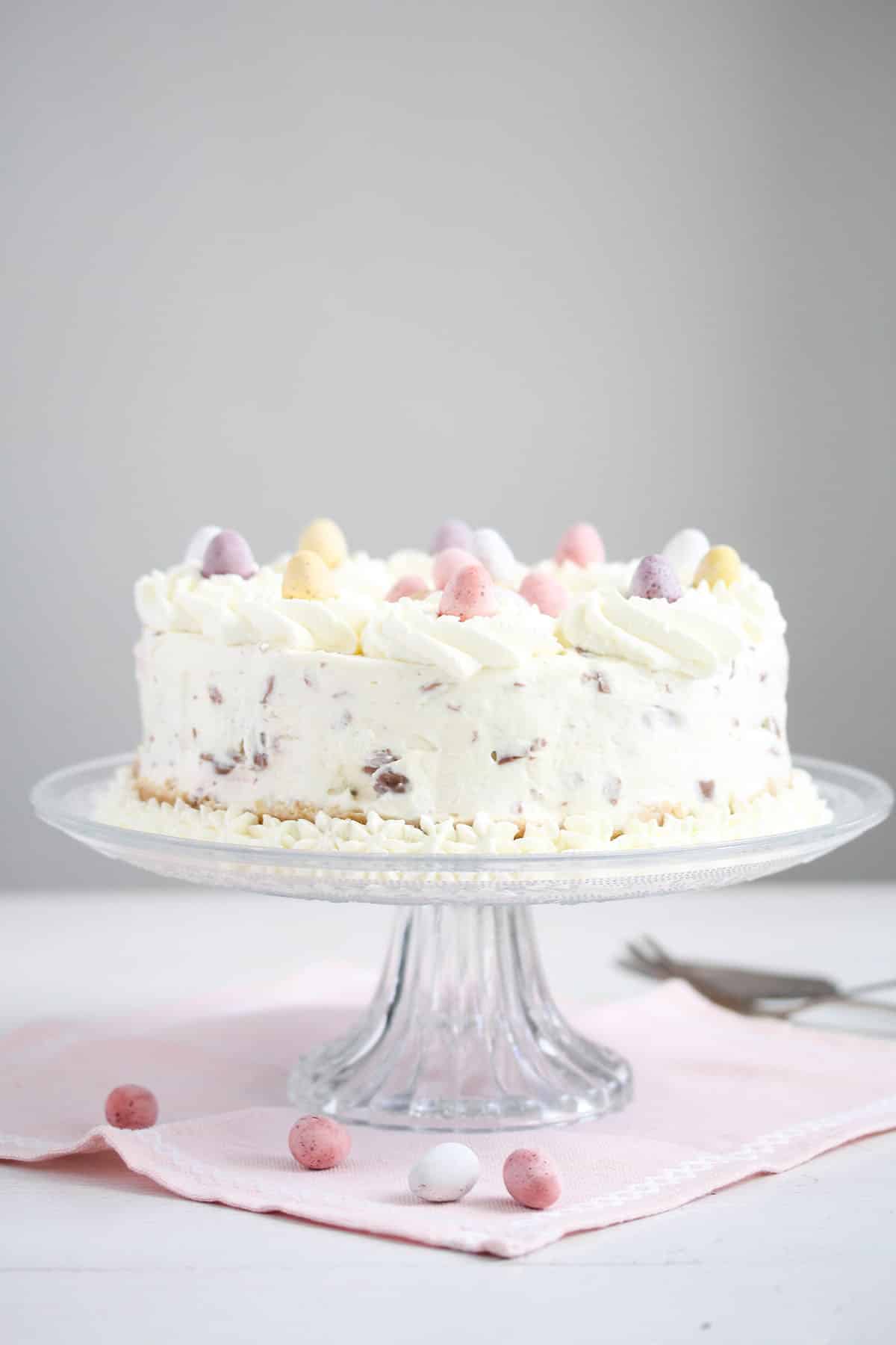 cheesecake with cadbury mini eggs on a high cake platter.