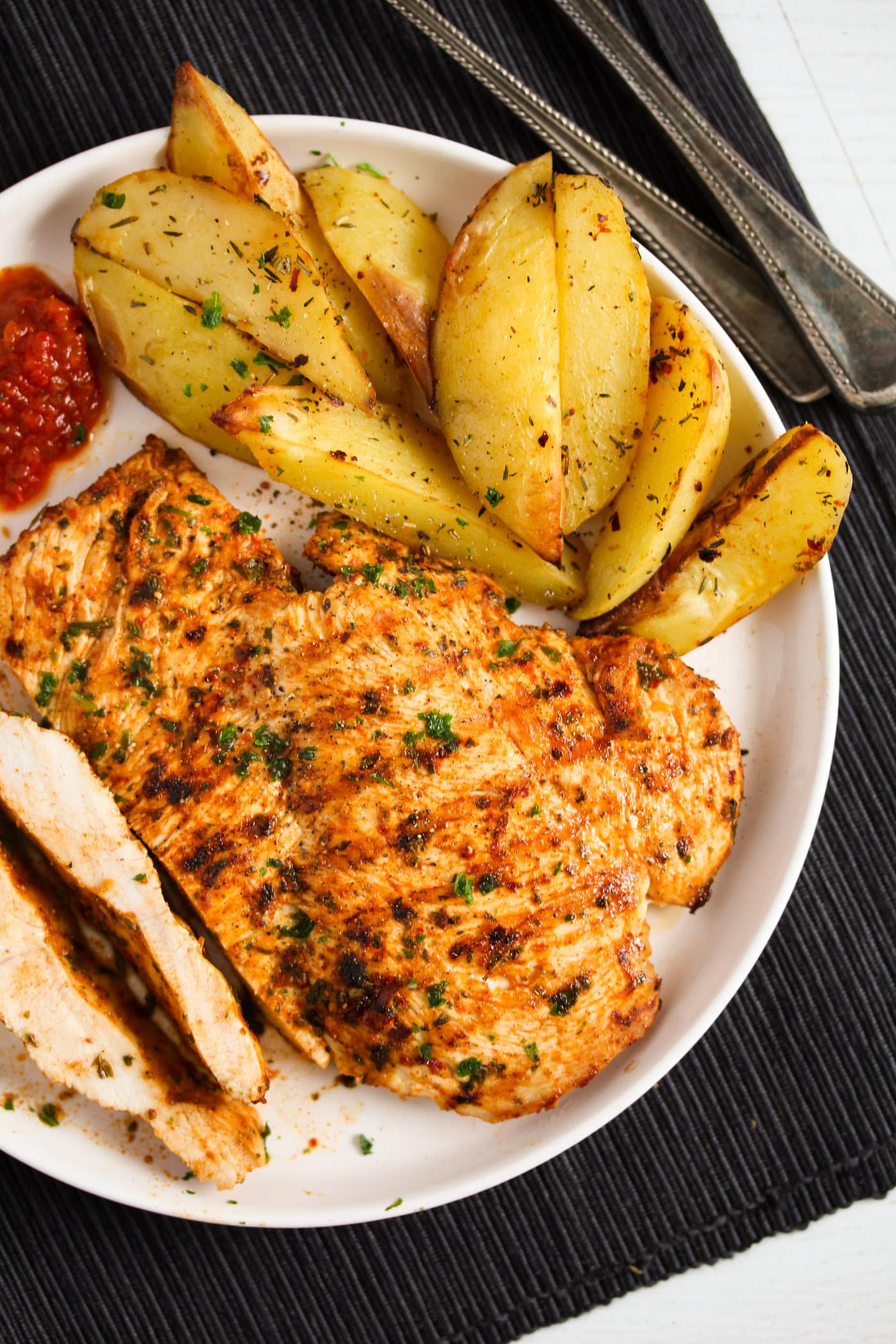 sliced grilled nando's chicken breast with oven potatoes and dip.