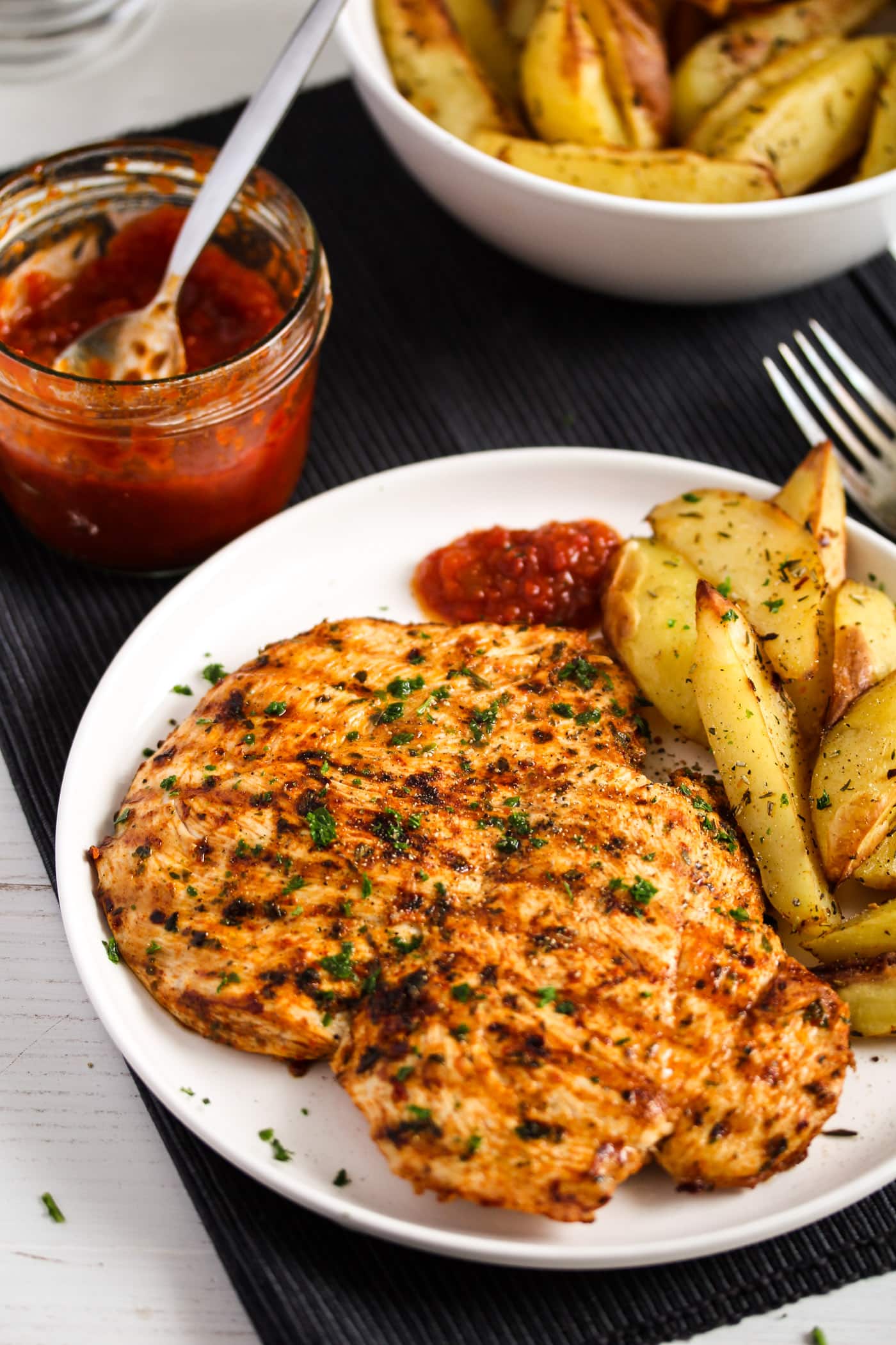 plate with peri peri chicken, potatoes and sauce.