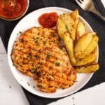 nando's butterfly chicken breast served with roasted potato wedges and peri peri dip.