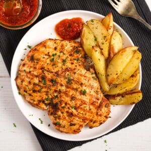 nando's butterfly chicken breast served with roasted potato wedges and peri peri dip.