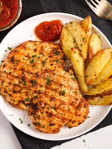 nando's butterfly chicken served with potatoes on a white plate.
