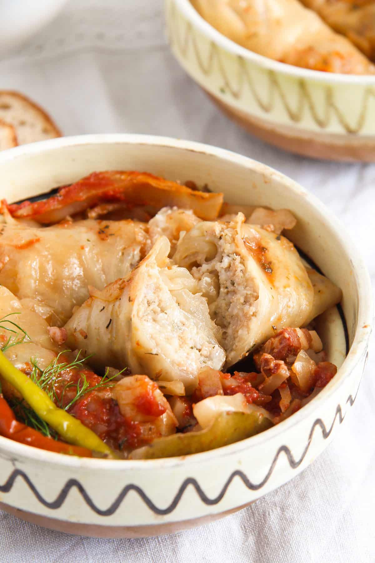 romanian cabbage rolls split to show the filling in a vintage bowl.