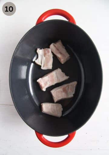 fatty pieces of smoked pork ribs in a oval dutch oven.
