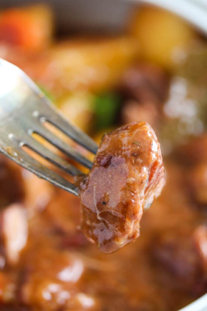piece of glossy meat held by a fork.